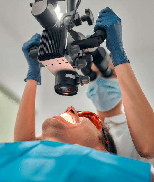 Endodontist adjusting overhead lamp while working with a patient