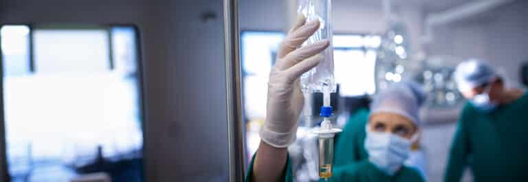 Doctors in surgery room with close up on IV drip.