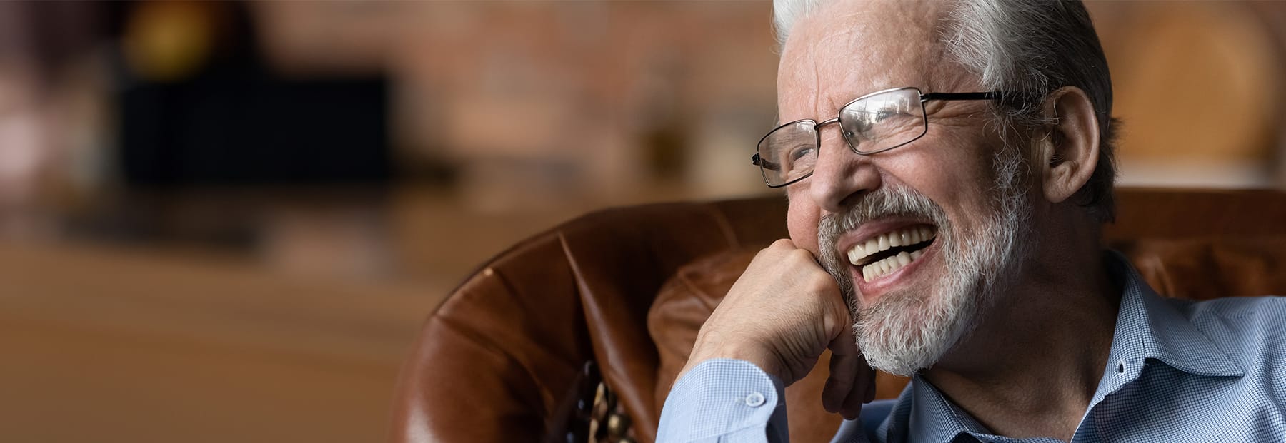 Elder person glasses smiling revealing a full set of dental implants.