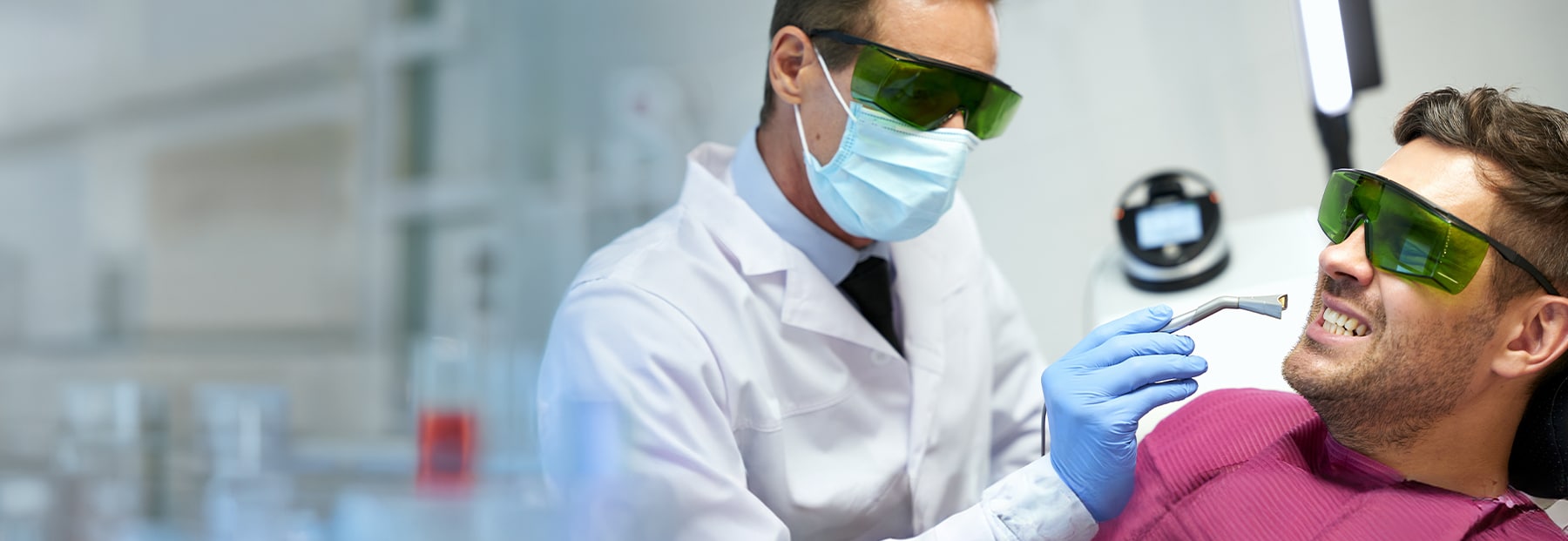 Patient and doctor wearing light-protected-glasses as patient performs laser dental treatment.