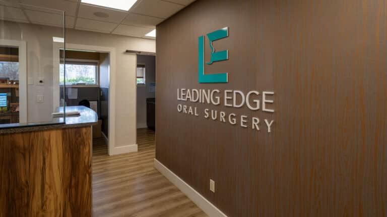 Interior Bay Shore office with green Leading Edge logo against walnut-brown wall.