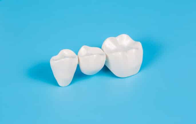 Plastic dental crowns against a blue background.