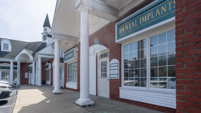 Front door to the Eastern Long Island Oral Surgery location along side a red brick building.