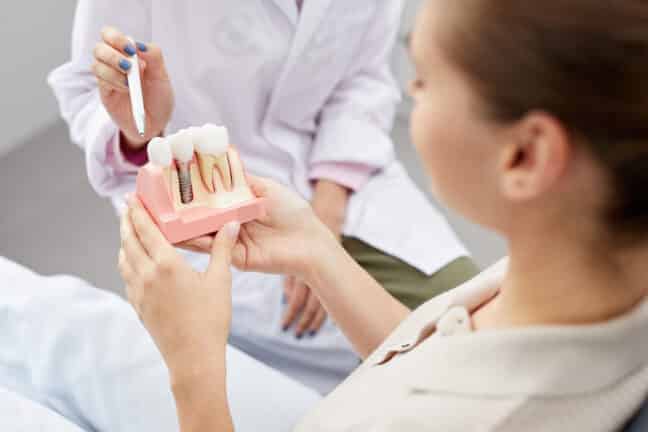 Patient holding tooth implantation model.