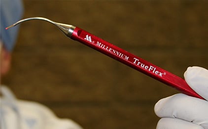 Red low level laser tool in the hand of a dentist.