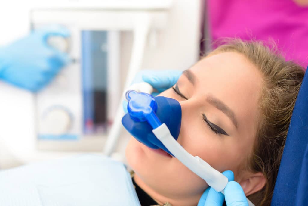 Patient with mask on for inhalation sedation at dental clinic.